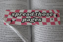 handmade bookmark with pink and white checkers and text that reads 'spread those pages'