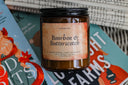 Bourbon & Butterscotch candle in bourbon whiskey, cream, and butterscotch scent on festive books