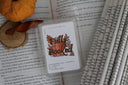 Scented wax melt packaging labeled 'Fully Booked' on a book page with autumn decorations.