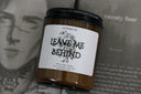Candle jar labeled 'Leave Me Behind' displayed against an open book
