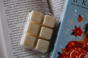 Pack of book-themed, non-toxic wax melts next to a book with a colorful cover