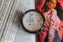 Snowfall in Solaria book-themed candle top view with blue sprinkles and wooden wick