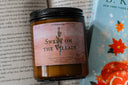 Romantasy book-themed candle labeled 'Sweet on the Villain' on a book with a colorful cover.
