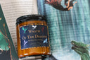 Candle labeled 'Wrath of the Dragons' with dragon illustrations on a book background