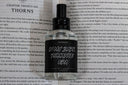 Bottle of perfume for the scent 'In MY Dark Romance Era' displayed on an open book