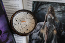 Book-themed candle in front of fantasy book with ethereal woman in flowing gown